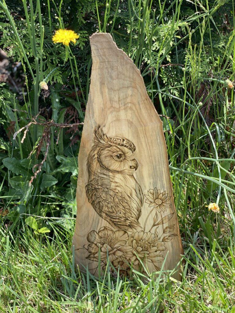 An owl and floral arrangement burned on wood